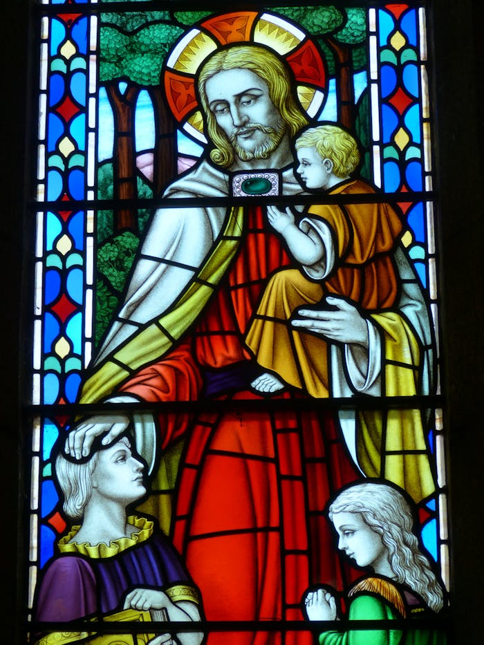 Stained glass window featuring a biblical scene with Jesus and worshippers in vivid colors.